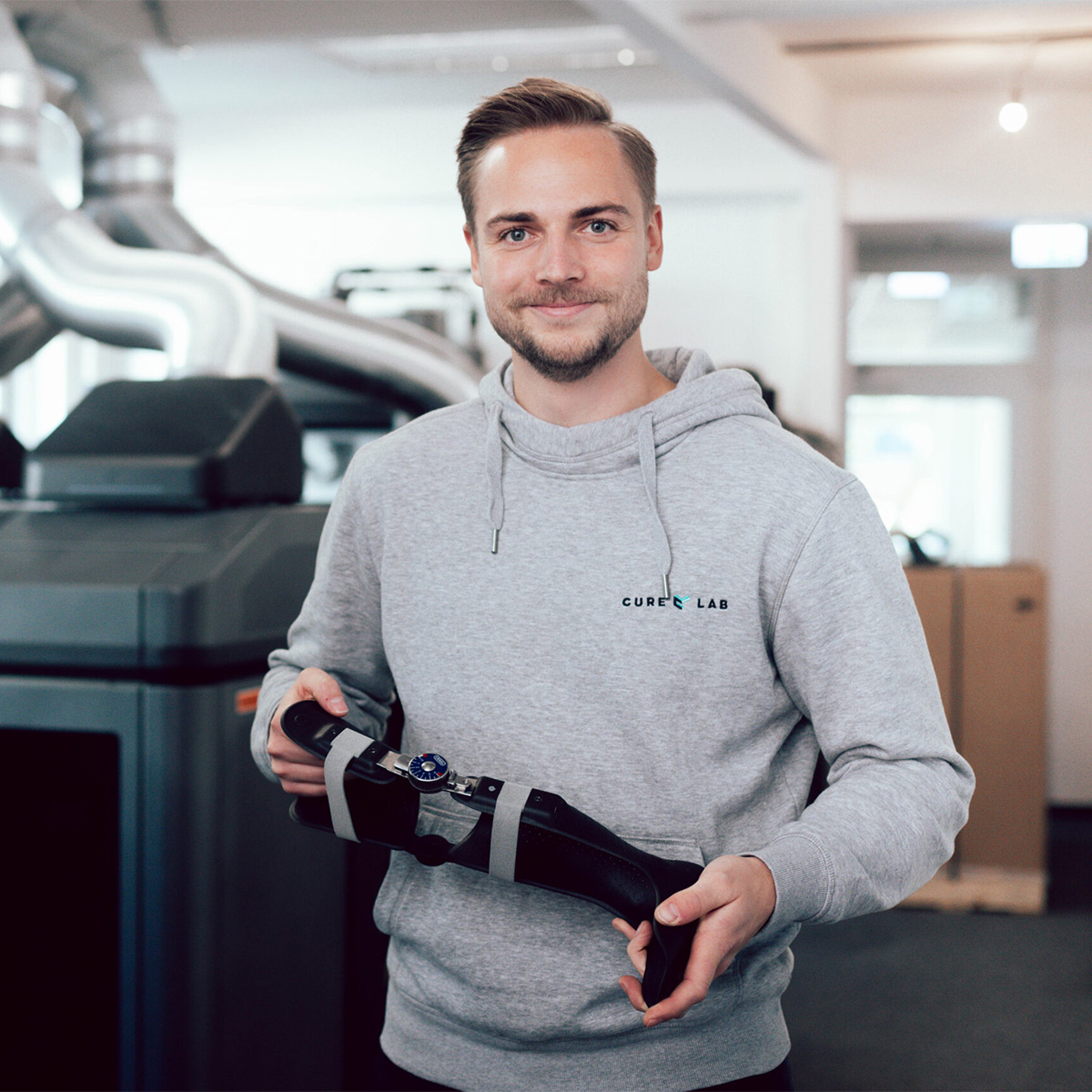 Mann-hält-3D-Druck-Prothese-und-lächelt-in-die-Kamera